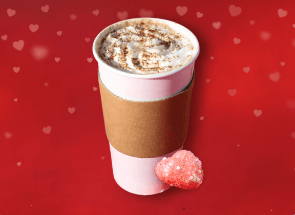 Latte with caramel and whipped cream on top. Red Background with hearts